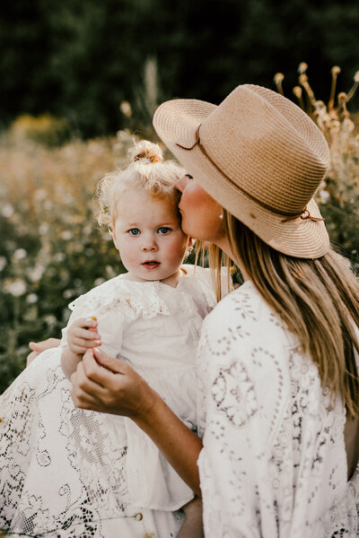 en mamma och ditter sitter på ett blomfält och myser