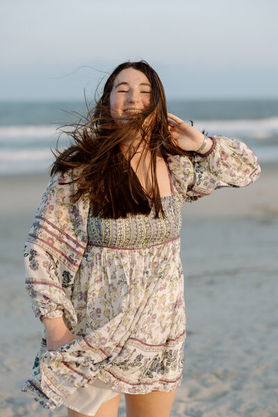 Senior walks on the beach while the wind blows her hair