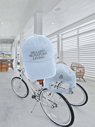 Dillard Signature Living branded baseball cap in coastal blue, shown front and back, embroidered with both logo type and monogram.