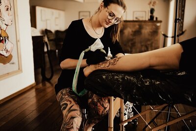 Tatuerare Beccsla tatuerar kunds ben.
