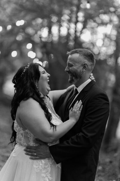 black and white wedding photo of groom holding his bride as she laughs as they elope to Gatlinburg in the woods captured by gatlinburg photographers
