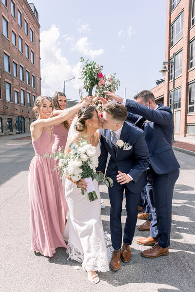 Bride and groom kissing surrounded by the bridal party