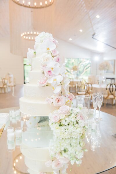wedding cake on a table decorated with florals and drinking glasses