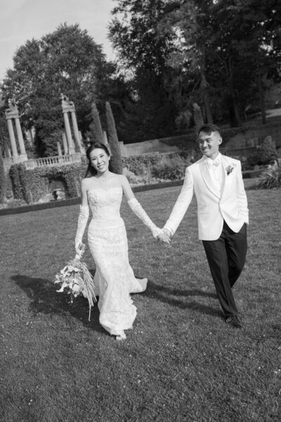 bride and groom holding hands and smiling and laughing and walking through crane estate ipswich taken by boston documentary wedding photographer