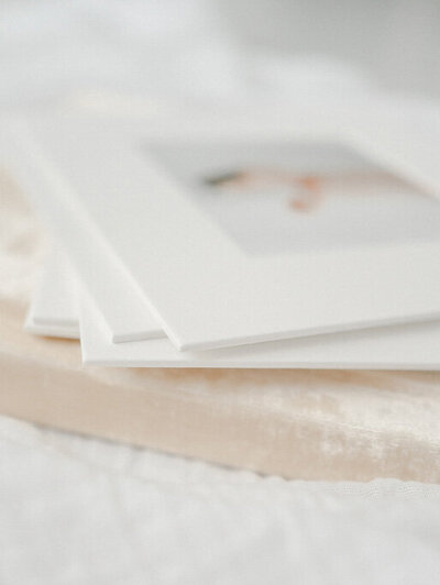 A close-up of matted fine art prints stacked on a velvet album cover — Raleigh portrait photographer.