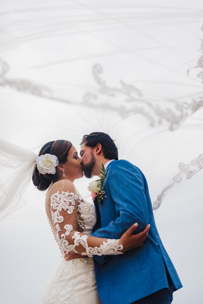 bride and groom kissing under veil luxury wedding photography