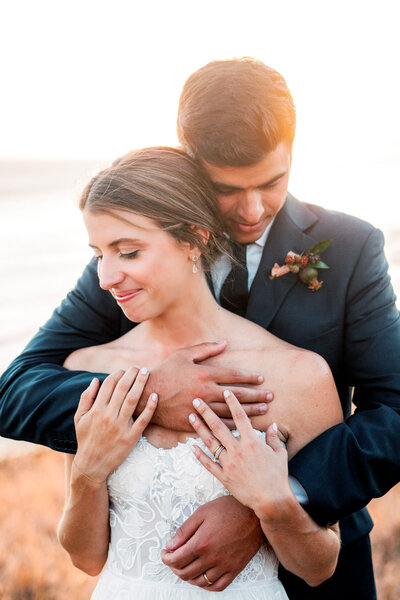 Groom embraces his smiling bride at sunset after their Santa Barbara wedding