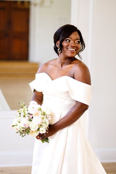 A bride holding a bouquet of flowers as she looks over her shoulder.