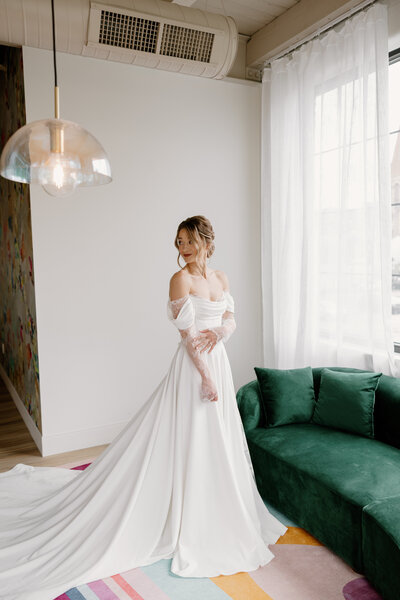Bride posing in an a-line gown in front of a green velvet couch.