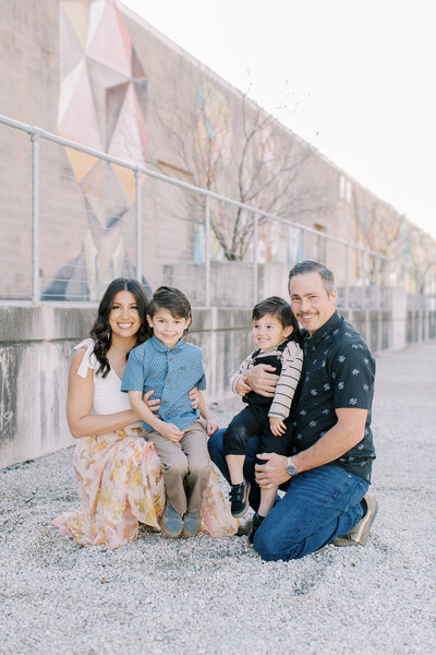 Mother and father hold their two young boys for family portrait at park