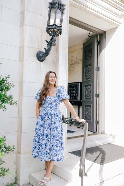 Girl in blue and white toile dress stands outside of DC Building