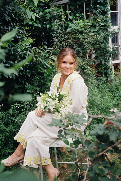 A picture of Kate sitting in a chair holding a bouquet of flowers.