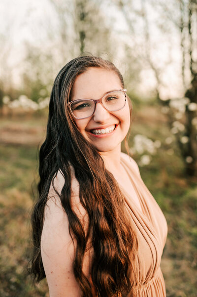Springfield MO Photographer Jessica Kennedy of The XO Photography standing in field holding camera smiling