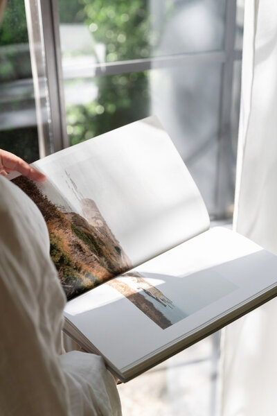 Woman flipping through pages of a book that shows the scenic views of C