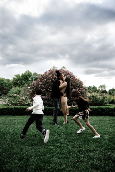 Couple embracing as their children run circles around them