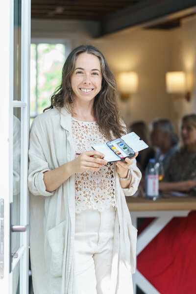 Austin Watercolor Artist and Watercolor Teacher Jaime Reynolds  Poses in front of her in person workshop in a beautiful Austin, Texas location