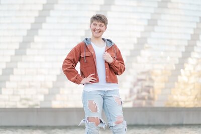a young person smiling posed with her hand on her jacket