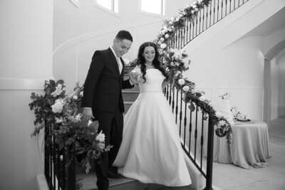 An Austin-based wedding photographer captures a bride and groom descending a staircase in a timeless black and white photo.