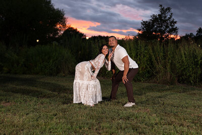 A couple in a field both leaning over and posing together 