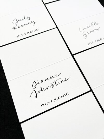 White tented escort cards with black ink calligraphy