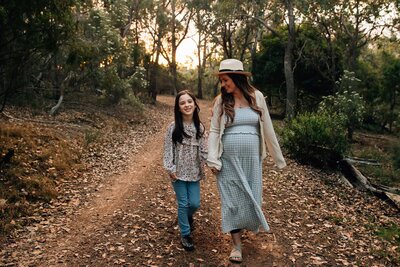 Sunset maternity photography session, mother and daughter walking down bush lane together.