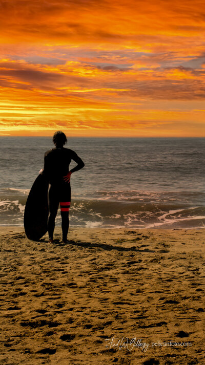 Shortboard surfer ponders the surf across the vast Pacific Ocean from the shore of Monterey Bay in Santa Cruz, CA.