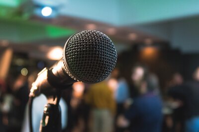 Photo of a microphone with a blurred crowd behind it