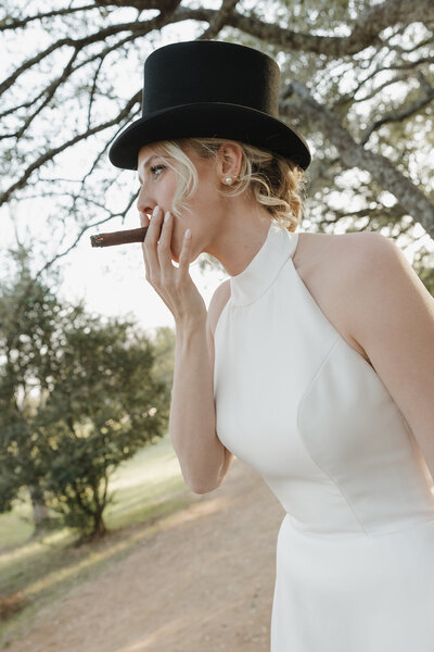Bride smoking a cigar with a top hat on.