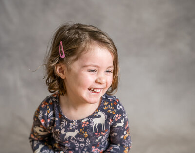 A school aged girl closes her eyes and laughs while biting her lip on school picture day in Minneapolis, MN.