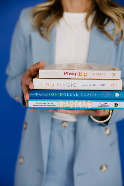 Heather Frick executive coach wearing a blue blazer and holding a stack of coaching books