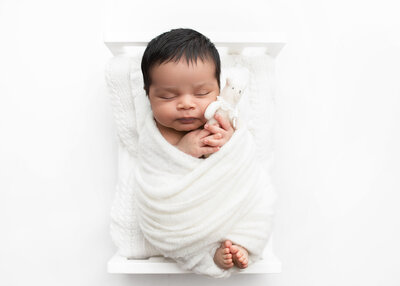 Sleeping Newborn baby wrapped in a natural blanket and swaddled for a studio newborn photography session by Lauren Vanier Photography