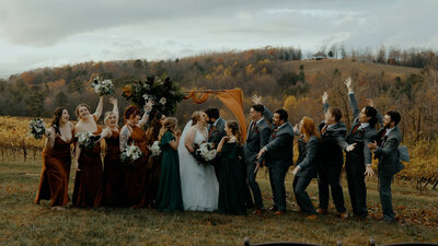 Wedding ceremony in a colorful field, bride and groom surrounded by friends near the arch.