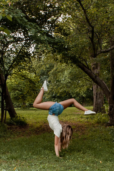 Image of graduating high school senior doing a handstand in a nature setting. 