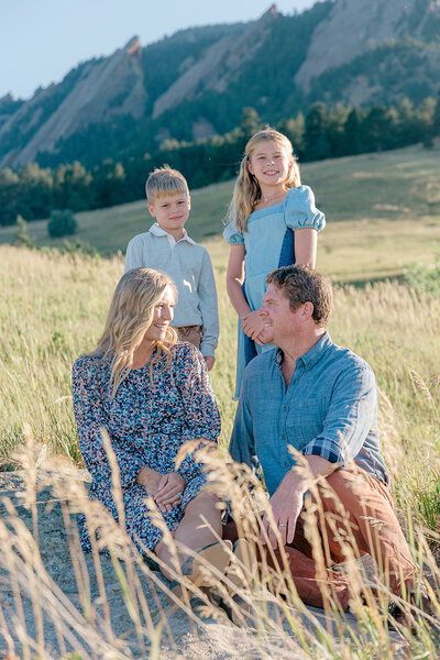 Family of four at Chautauqua Park in Boulder Colorado. Parents are sitting and looking each other, kids are looking at the camera.