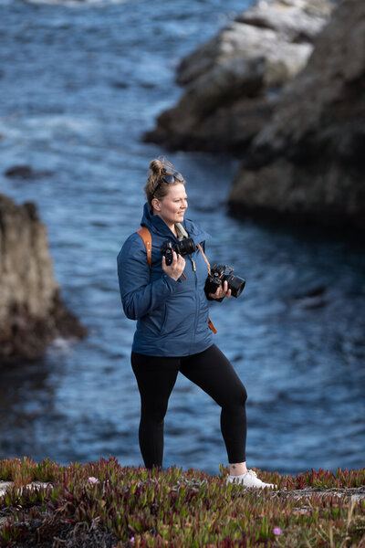 girl holding cameras on big sur coastline