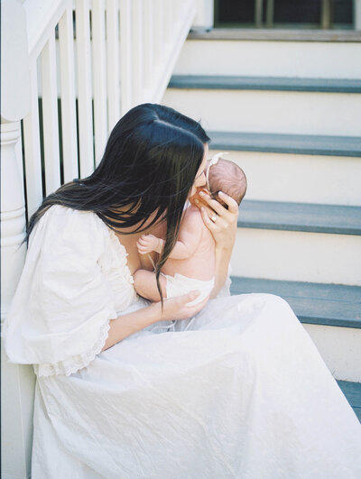 Mother in white Doen dress holding newborn daughter and son's hand in front of a window on fuji 400h by Richmond VA Family Photographer