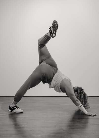 Black and white image of Alex Paige doing a headstand yoga position on a mat