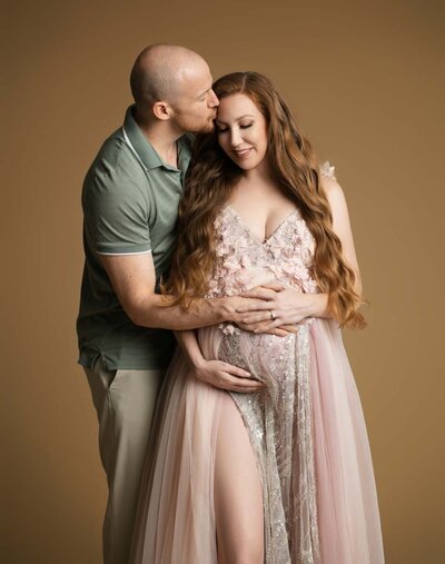 Beautiful woman wearing a purple dress with a purple background for a maternity photoshoot in Orlando