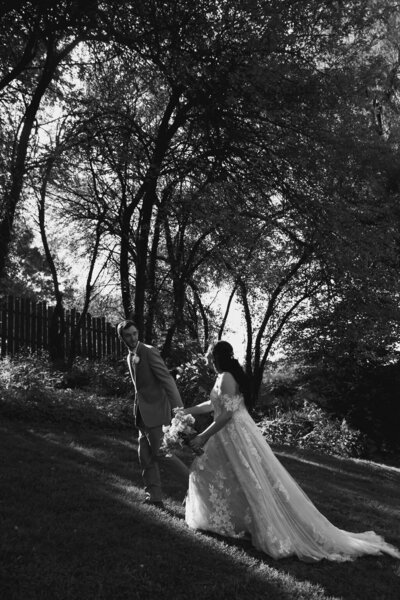 black and white image of a Bride and groom in the woods by a fence at Willowbrook