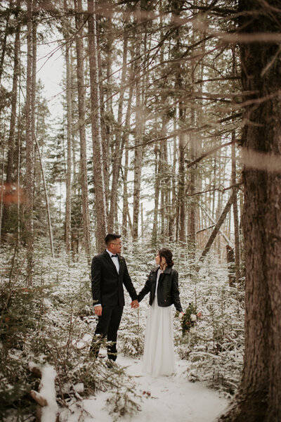 bride and groom holding hands in forest
