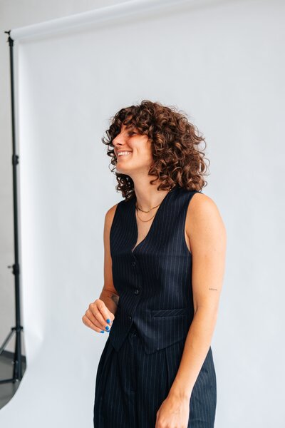 Vrouw met krullend haar en zwart gilet tijdens branding shoot voor Studio Vers, voor persoonlijk webdesign