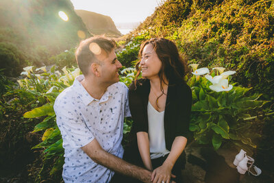 Sun flares roll into the frame during this couple's engagement session among cala lillies in California.