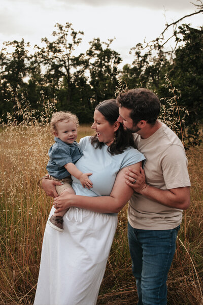 Loving family sharing a tender moment together in a golden grass and wildflower field during sunset, capturing warm natural light and connection.