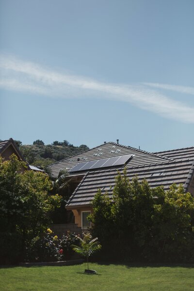 Residential home with sleek rooftop solar panels and landscaped backyard, showcasing sustainable living and energy independence