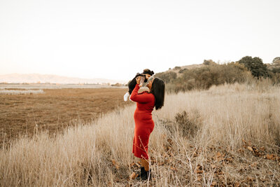 Mom holding newborn up in a field during golden hour.