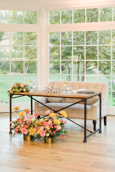 colorful florals in front of sweetheart table at indoor wedding reception