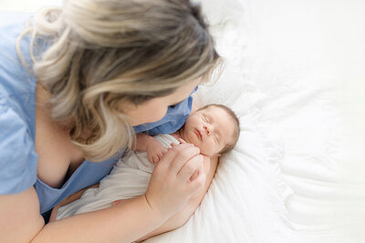 Peaceful Tampa newborn baby boy sleeping wrapped in soft neutral fabric held by mother during luxury studio session