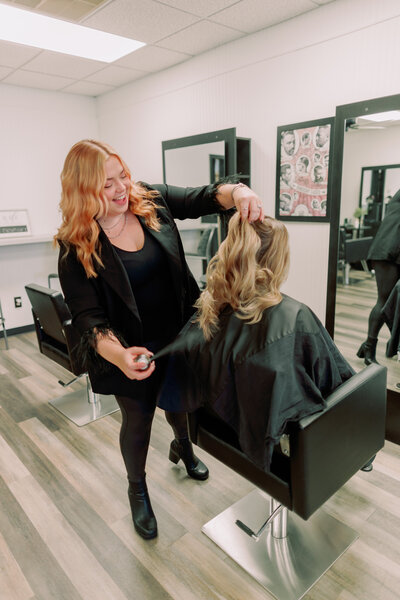 A hair stylist sprays a client's hair.