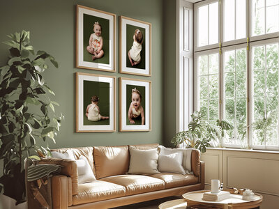Framed milestone portrait of a baby girl sitting on wood floor, displayed above a modern cabinet with minimal decor.