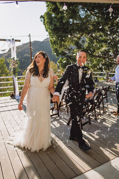 Bride and groom walk down aisle with confetti